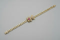 Gold chain bracelet with a bear head charm on a gray surface