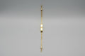 Gold bracelet with a nameplate on a gray surface