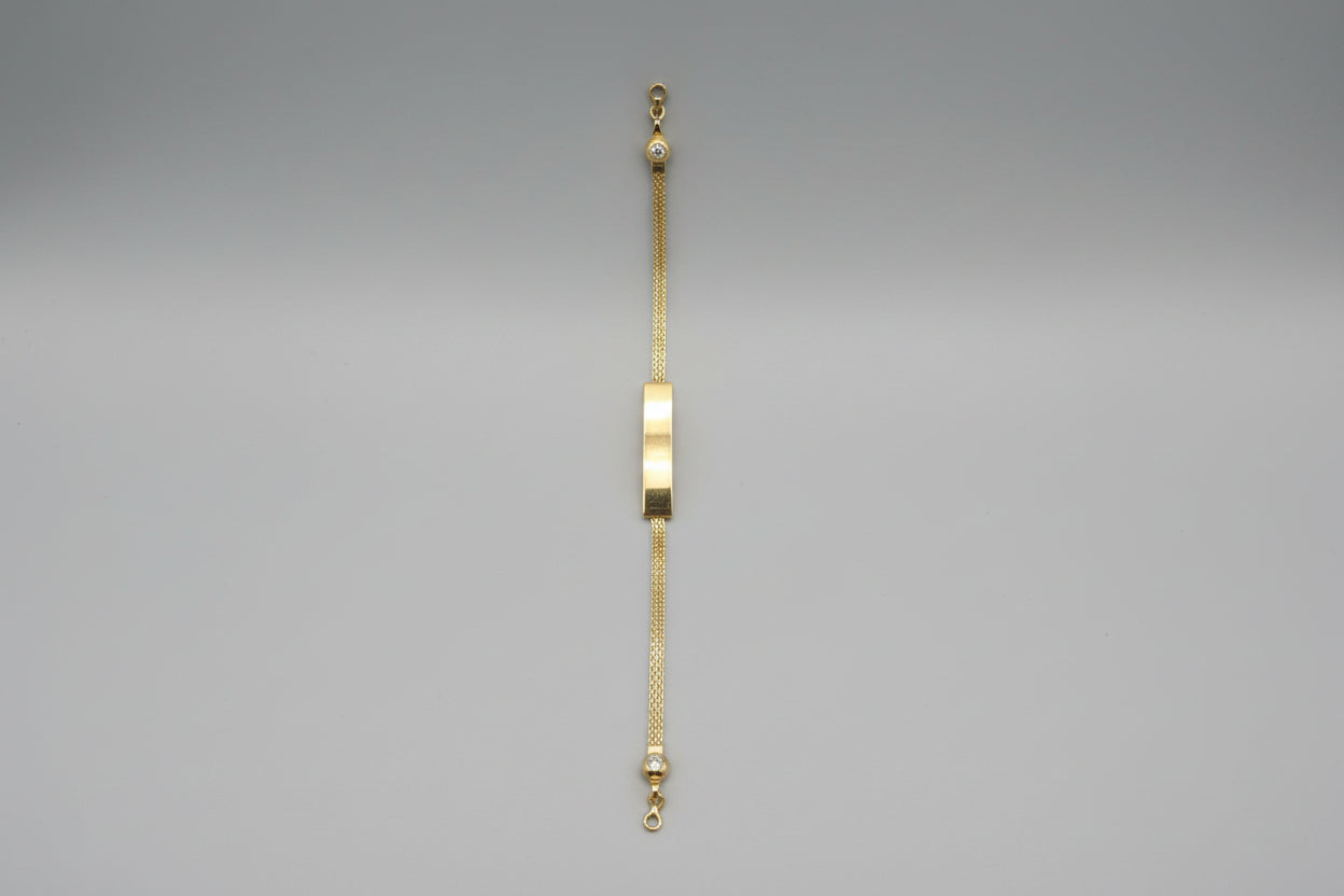 Gold bracelet with a nameplate on a gray surface
