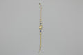 Gold bracelet with blue stones on a gray surface