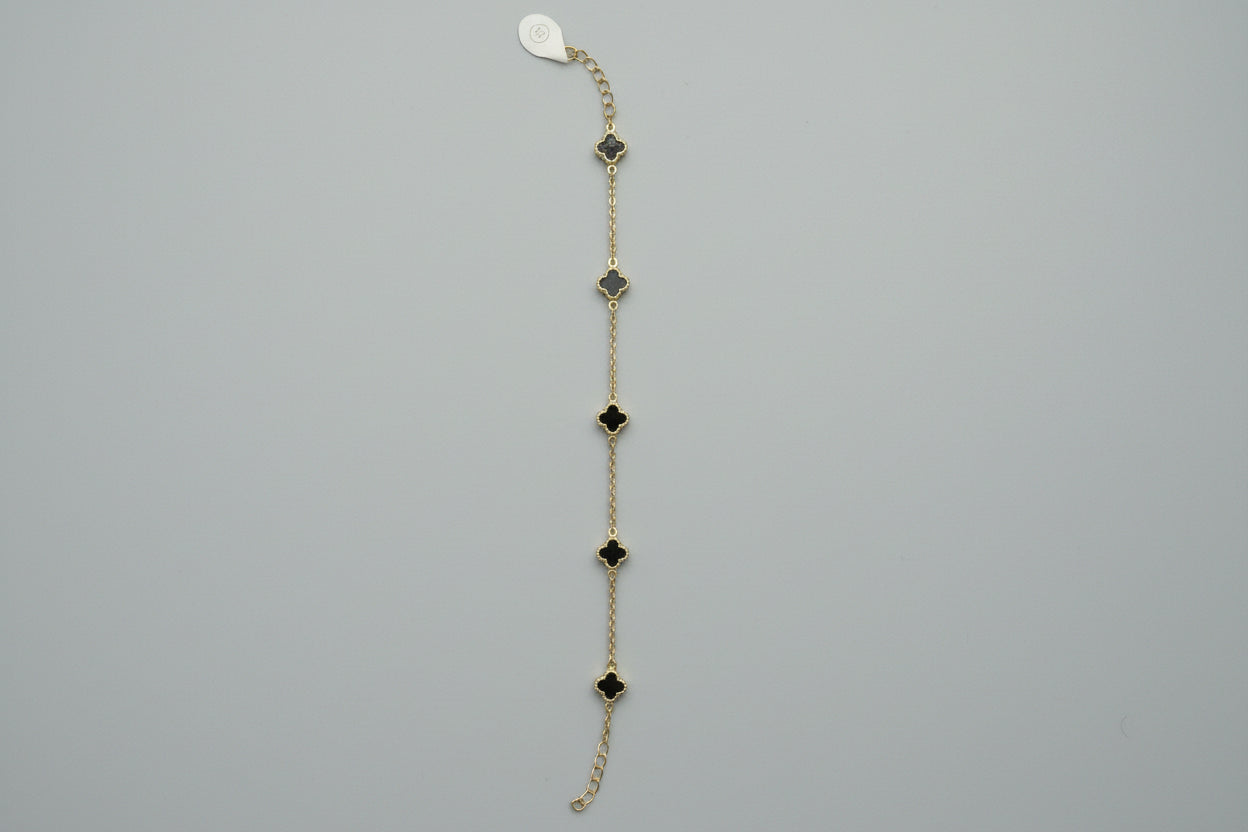 Gold chain necklace with black clover-shaped pendants on a mannequin.