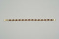 Gold bracelet with red stones on a gray surface