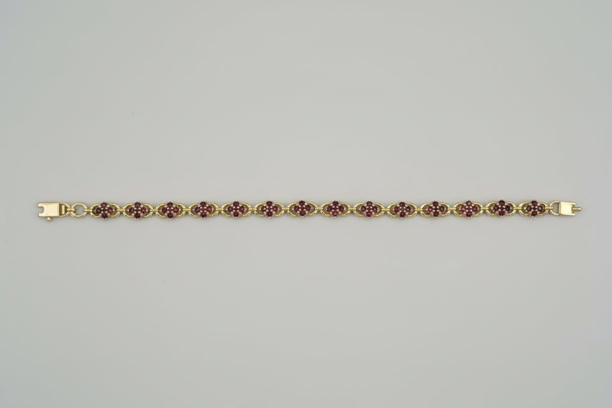 Gold bracelet with red stones on a gray surface